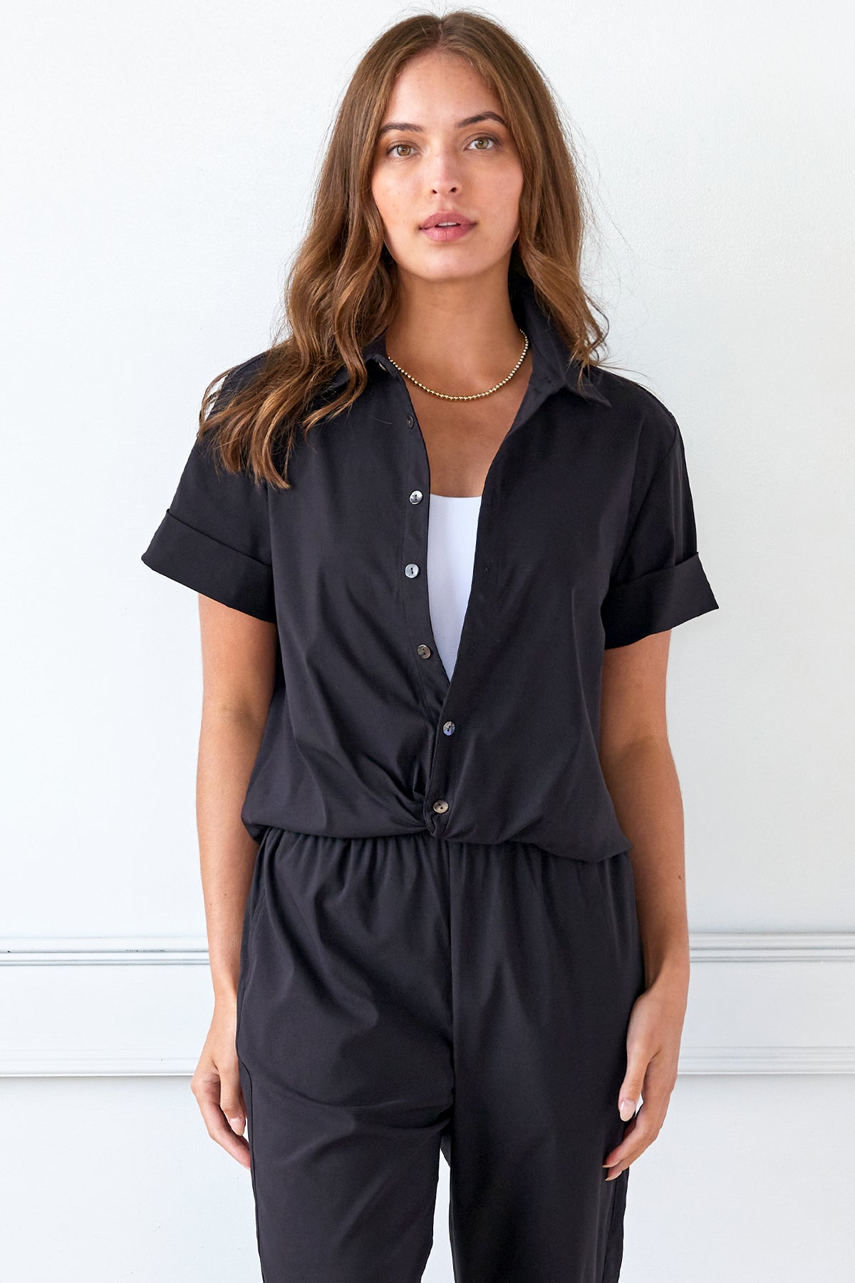 A model view of the Alli blouse in black, featuring a twist hem and a comfortable cropped fit.
