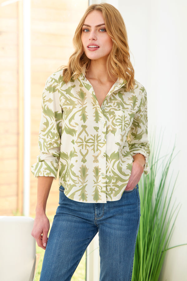 A model wears the Finley Andie blouse, a cropped cotton button down shirt with a point collar and a sage green stile print.