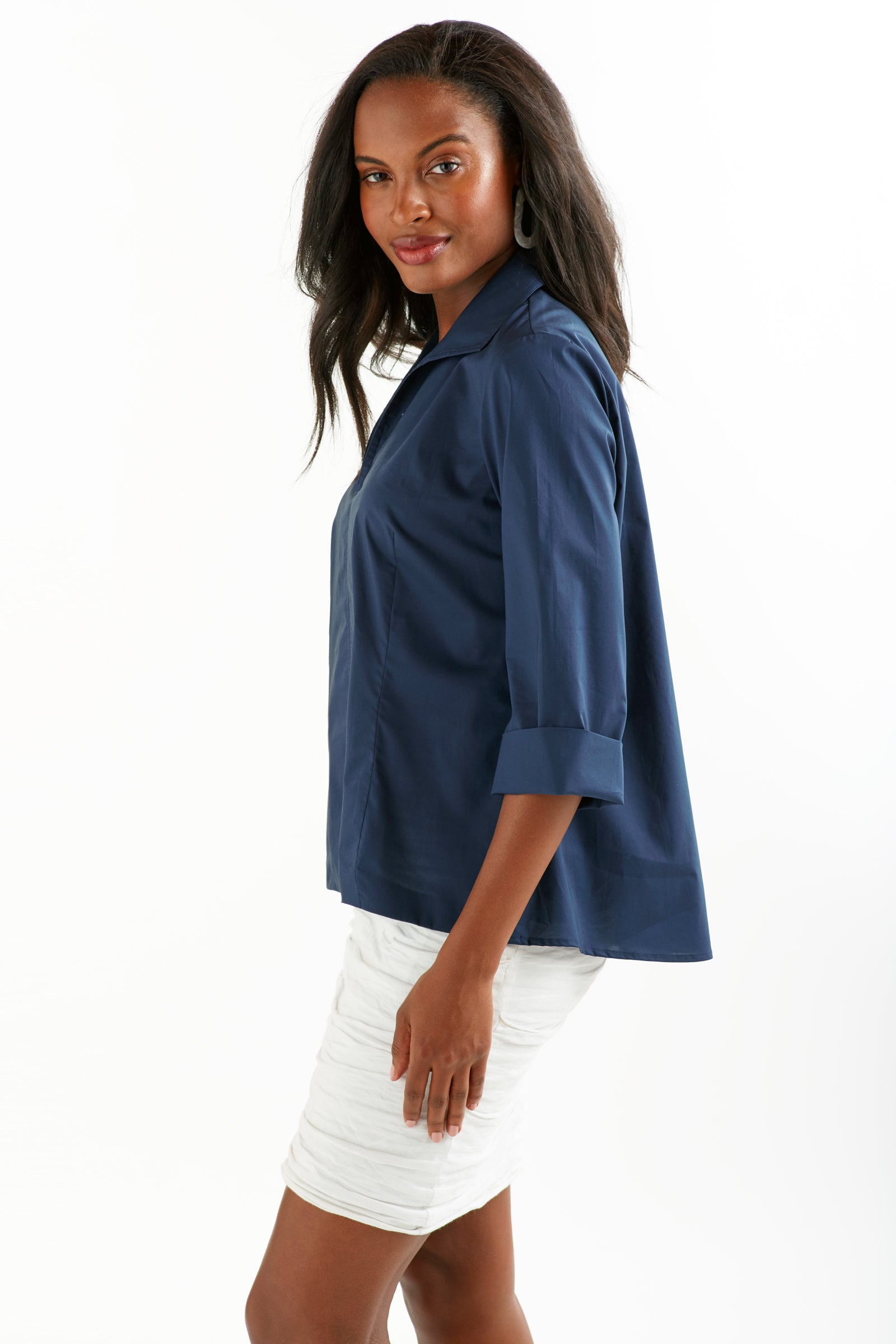 A womens model wearing the Finley swing shirt, a 3/4 sleeve navy v-neck popover with a relaxed shape and a back inverted pleat.