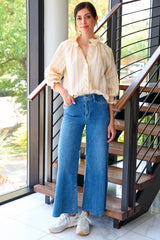 A supermodel wearing the Finley Fiona, a gray & yellow seersucker striped blouse with 3/4 blouson sleeves, a ruffle collar, and a relaxed contour.