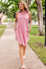 A model wearing the Finley swing dress, a red & white seersucker sleeveless shirt dress with an A-line silhouette.