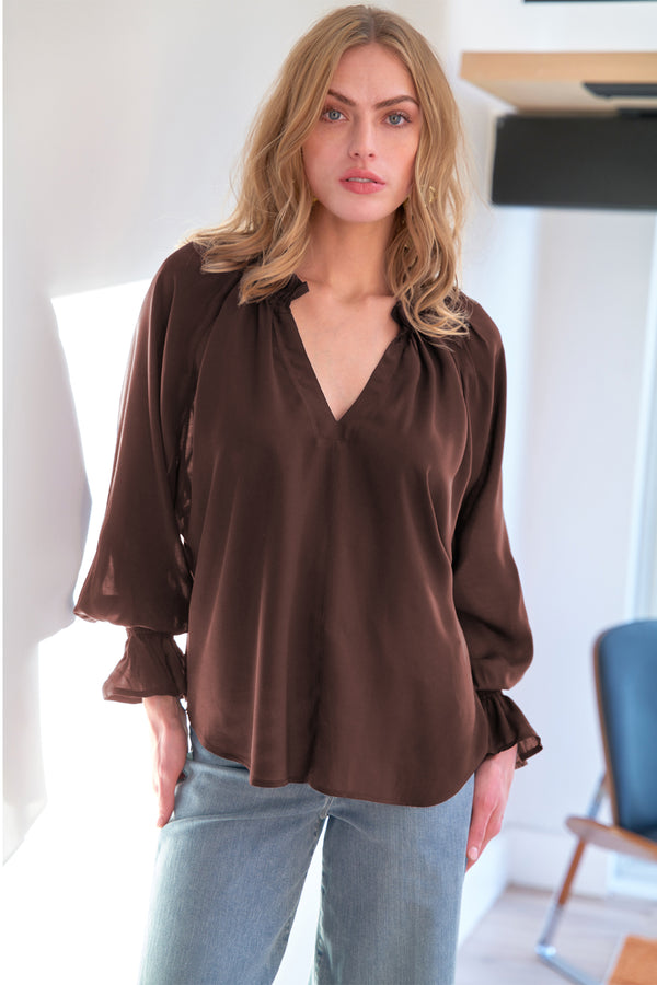 A model wearing the Finley Candace blouse, a espresso brown viscose voile popover top with long blouson sleeves and a v-neck.