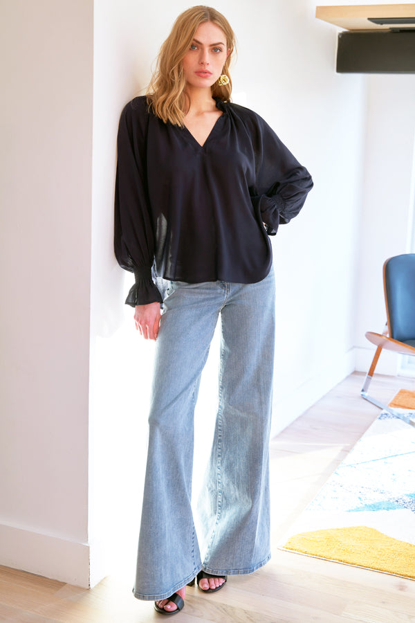 A model wearing the Finley Candace blouse, a navy blue viscose voile popover top with long blouson sleeves and a v-neck.