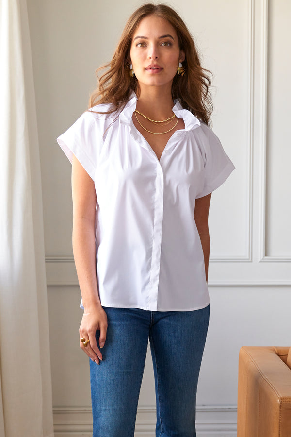 A model wearing the Finley Jenny blouse, a short sleeve denim blue hemp cotton blouse with ruffle collar detail and a relaxed shape.