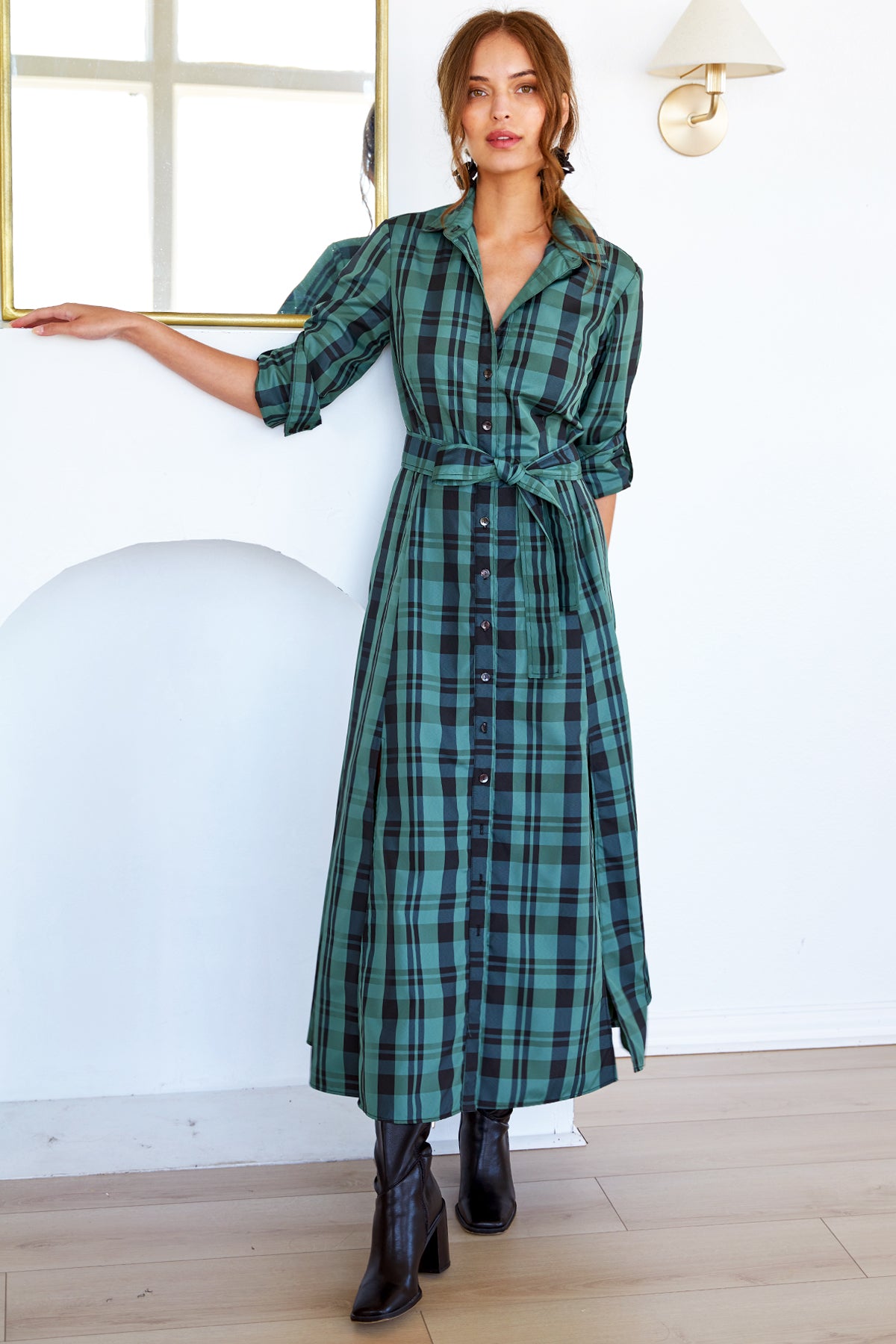 A model wearing the Laine tie-front maxi dress in emerald green plaid polyester with an A-line silhouette.
