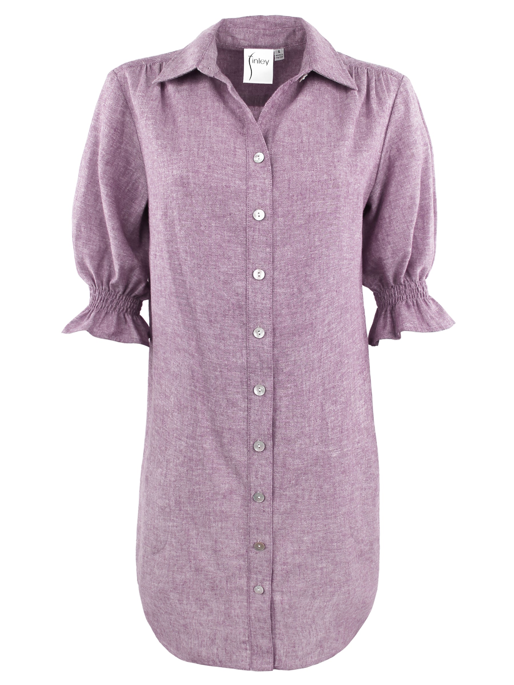 A model wearing the Miller shirt dress, made from a hemp cotton blend in lavender purple with elbow-length puff sleeves, chambray fabric, and pockets.
