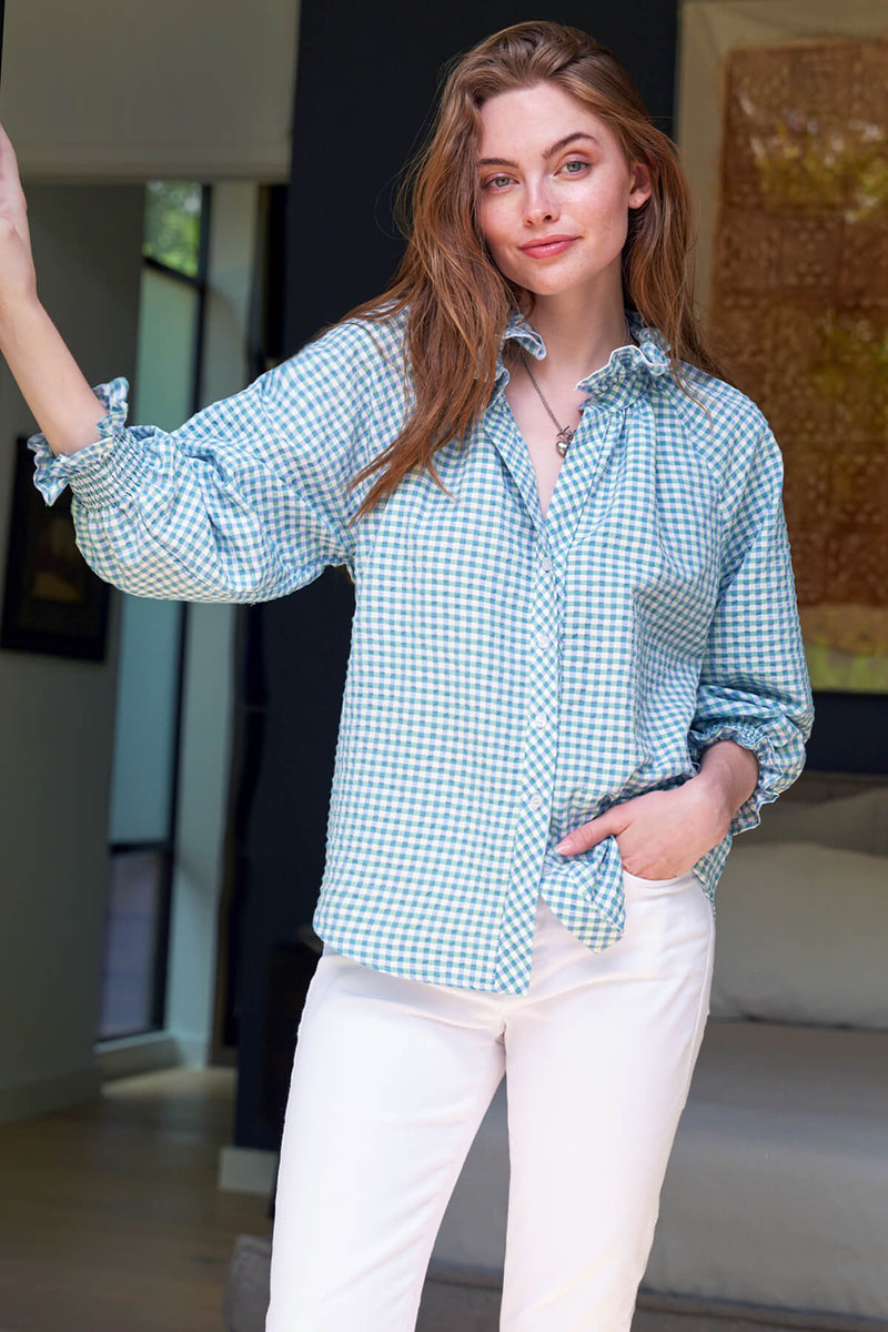 The Finley Fiona blouse, a button down top with puff sleeves, a ruffle neckline, and a green & yellow seersucker pattern.